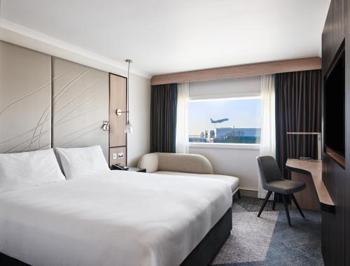 a hotel room with a bed and a desk and a window at Hyatt Place London Heathrow Airport in Hillingdon