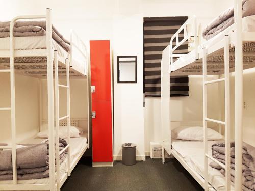 a dorm room with bunk beds and a red door at One Way Guesthouse Busan in Busan