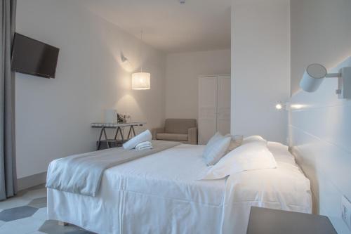 a white bedroom with a bed and a chair at Hotel Villa Ambra in Orbetello