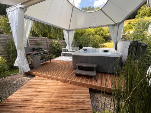 bañera de hidromasaje en una terraza de madera bajo una tienda blanca en Lodge spa privatif Starlette, séjour zen, en Meisenthal