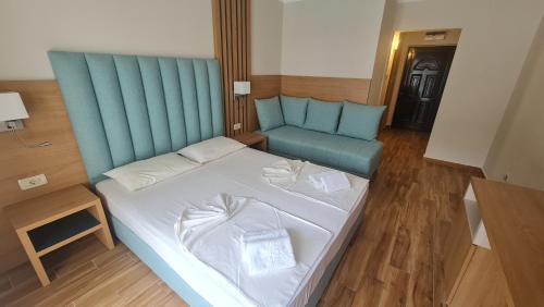 ein Schlafzimmer mit einem Bett und einem blauen Sofa in der Unterkunft Vile Oliva Hotel & Resort in Petrovac na Moru
