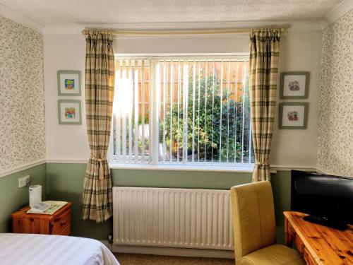 um quarto com uma cama, uma janela e uma cadeira em Blythewood Guest House em Coleshill