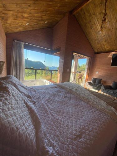 ein großes Schlafzimmer mit einem großen Bett und einem großen Fenster in der Unterkunft Chalé Veneza Caravaggio in Santa Teresa