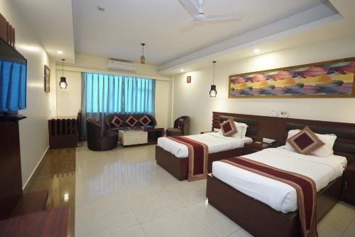 Habitación de hotel con 2 camas y sofá en HOTEL AVN GRAND, en Ranchi