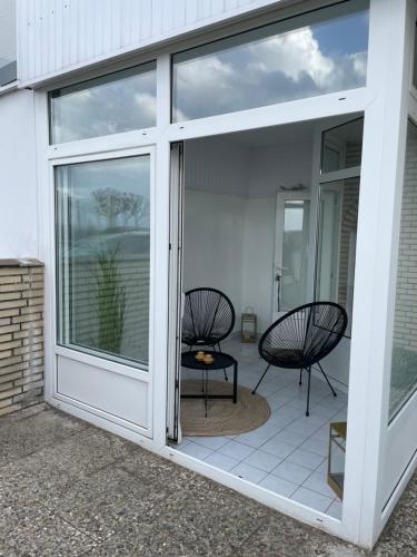 a sliding glass door leading to a patio with two chairs at Juna in Laboe
