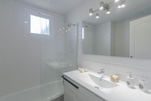 Apartamento Small Oasis Manilva في مانيلفا: حمام أبيض مع حوض ومرآة