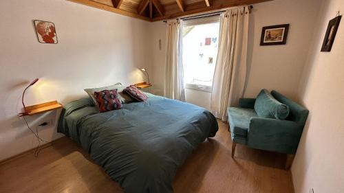 une chambre avec un lit, une chaise et une fenêtre dans l'établissement Hermoso departamento en el centro de SMA con balcón. 4/2, à San Martín de los Andes