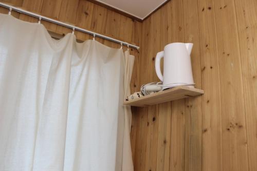 a bathroom with a white shower curtain and a shelf at Hostel JL in Chung-jeong in Seoul