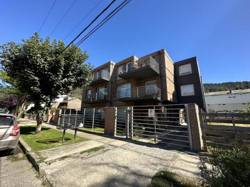 un bâtiment avec une clôture devant lui dans l'établissement Hermoso departamento en el centro de SMA con balcón. 4/2, à San Martín de los Andes