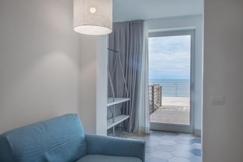 a living room with a blue couch and a balcony at Hotel Villa Ambra in Orbetello