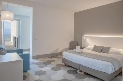 a white bedroom with a bed and a large window at Hotel Villa Ambra in Orbetello