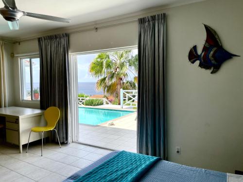 a bedroom with a bed and a desk and a pool at Villa Happy View in Willibrordus