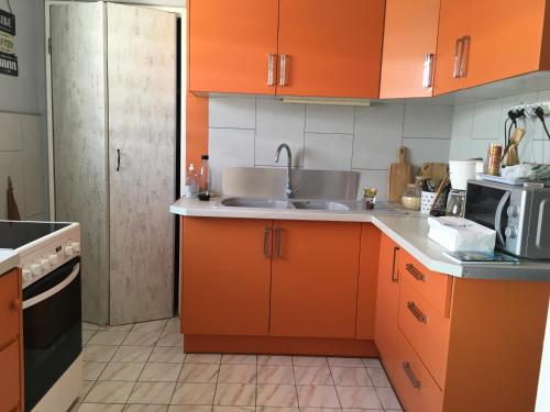- une cuisine avec des armoires orange et un évier dans l'établissement Le Bois Saint Martin, à Filaos