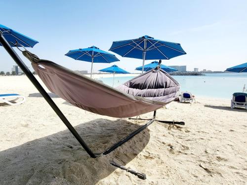 a boat sitting on a beach with umbrellas at Luxurious Studio Pacific Al Marjan Island - beachfront property in Ras al Khaimah