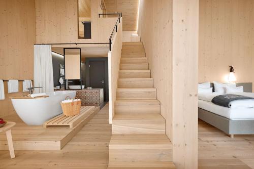 a bedroom with a staircase leading to a bed and a tub at Kulturhof Stanggass in Bischofswiesen