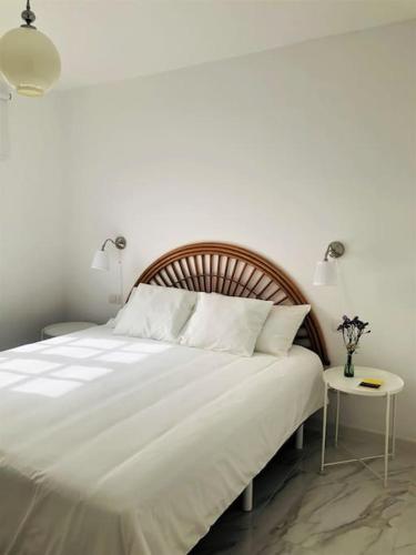 a bedroom with a large white bed with a side table at Casa Nicolás in Playa Honda