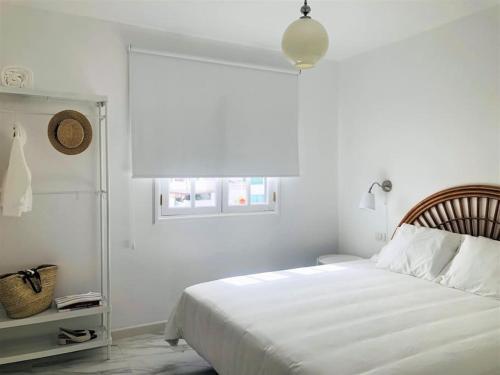 a white bedroom with a bed and a window at Casa Nicolás in Playa Honda