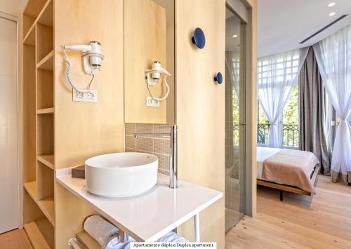 a bathroom with a sink and a bedroom at Gòtic by The 5ve Soul in Barcelona