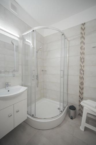 a white bathroom with a shower and a sink at Hőforrás Hotel in Gyula