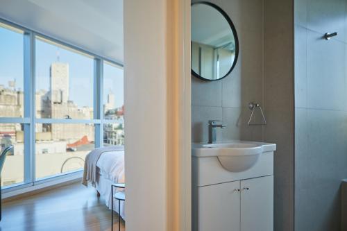 uma casa de banho com um lavatório, uma cama e um espelho. em Bellini Esmeralda by RentinBA em Buenos Aires