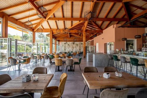 ガヴォッラーノにあるIl Pelagone Hotel & Golf Resort Toscanaの木製の天井、テーブルと椅子のあるレストラン