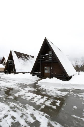 a cabin covered in snow in a parking lot at Alpska kuća Lucy in Jasenak