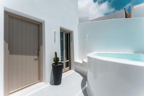 a door in a white house with a potted plant at AKRI santorini with heated jacuzzi in Emporio