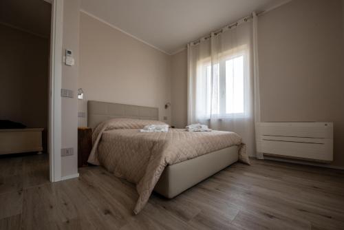 a white bedroom with a bed and a window at CASA TERMINEL in Villafranca di Verona