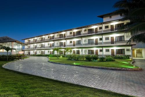 a large building with a cobblestone driveway in front of it at OYO Hotel Arembepe Beach Hotel, Camacari in Arembepe