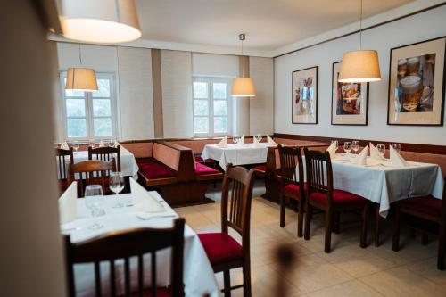 a dining room with white tables and chairs and windows at Gasthof Hartl & Hartl Stadl in Neuhaus