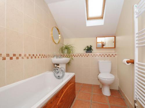 a bathroom with a toilet and a tub and a sink at Henwood Barn in Liskeard