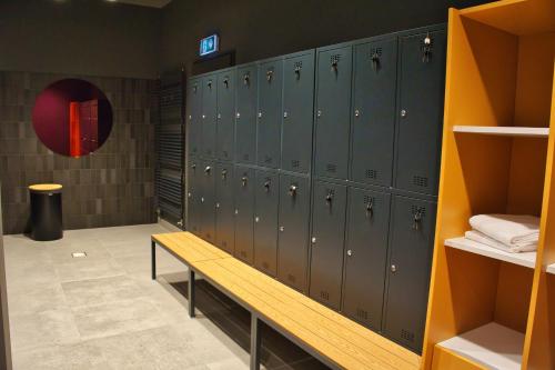 a locker room with green lockers and a wooden bench at Novotel Szczecin Centrum in Szczecin