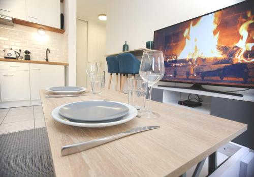 een tafel met borden en wijnglazen en een tv bij Charmant studio avec terrasse, refait à neuf in Aix-en-Provence