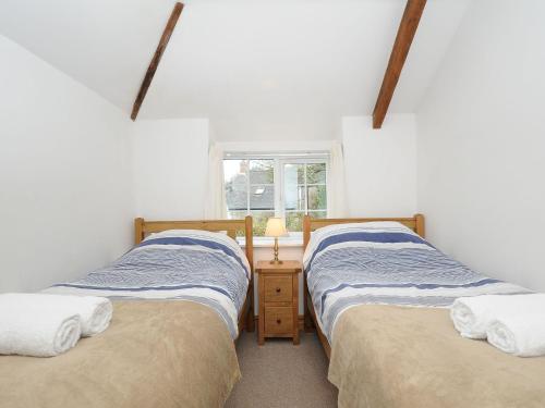 two twin beds in a room with a window at Small Barn in Liskeard