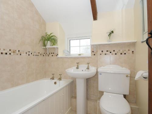 a bathroom with a toilet and a sink and a bath tub at Small Barn in Liskeard