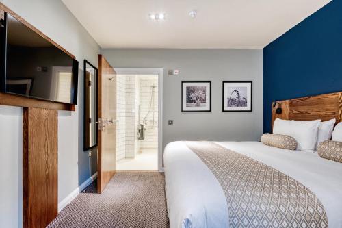 a bedroom with a large bed and blue walls at The Wheatsheaf by Innkeeper's Collection in Woking