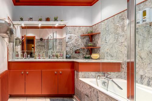 La salle de bains est pourvue de placards rouges, d'une baignoire et d'un lavabo. dans l'établissement artistmemory, à Corbeil-Essonnes