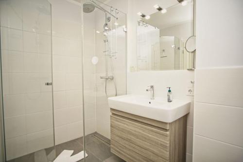 a white bathroom with a sink and a shower at zentrale FeWo mit Terrasse, gratis Nutzung vom AHOI Erlebnisbad und Sauna in Sellin - Villa Anni FeWo 02 in Göhren