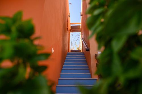 a stairway leading up to an orange building with blue stairs at AnnaDes Apartments & Studios Chios in Karfas