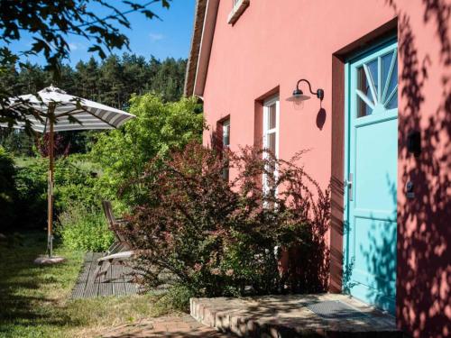 a pink house with a door and an umbrella at Landschek, Ferienhaushälfte "Das Ulmenhaus" in Morgenitz