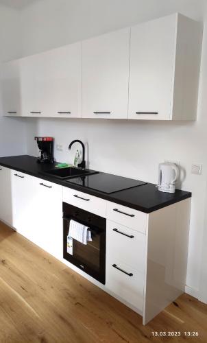 a kitchen with white cabinets and a black counter top at Krems am Campus in Krems an der Donau