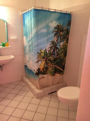 ein Badezimmer mit einem Duschvorhang mit Palmen in der Unterkunft Hotel Pension Streuhof Berlin in Berlin