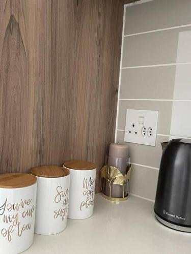 three coffee cups on a counter with writing on them at Home away from home in Avondzon