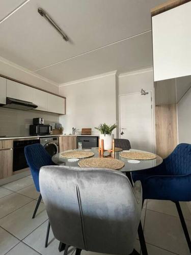 a kitchen with a table and blue chairs in a room at Home away from home in Avondzon