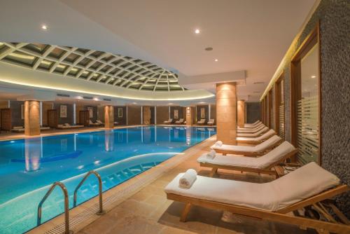 a large swimming pool with lounge chairs in a hotel at Badamdar Hotel and Residences in Baku