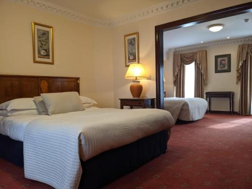 a hotel room with two beds and a mirror at Foley's Townhouse Killarney in Killarney