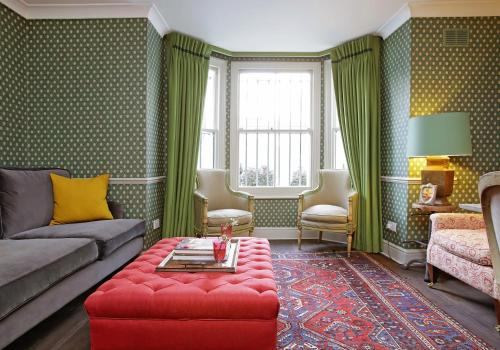 ロンドンにあるHome at Heart - Glorious 2 Bedroom Garden Apartment Notting Hill TALBのリビングルーム(ソファ、赤いオットマン付)