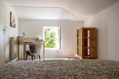 une chambre avec un lit, un bureau et une fenêtre dans l'établissement Maison au coeur du vignoble de Saint-Emilion, à Saint-Étienne-de-Lisse