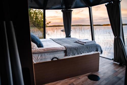 uma cama num barco com vista para a água em AuroraHut Aurantola em Kouvola