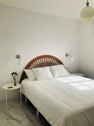 a bedroom with a large white bed and a table at Casa Eloína in Playa Honda